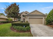 Two-story house with a beige facade, attached garage, and manicured lawn at 4074 Sw 47Th Ct, Ocala, FL 34474