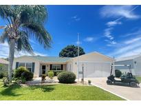 Charming single-story home with a well-manicured lawn, lush landscaping, and a convenient attached two-car garage at 9581 Se 168Th Elderberry Pl, The Villages, FL 32162