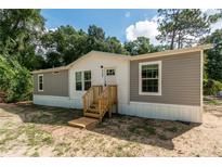 Gray and white mobile home with wooden steps and landscaping at 1143 Se 159Th Ct, Silver Springs, FL 34488