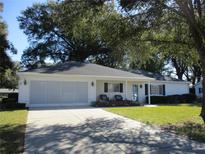 Single-story home with a white exterior, a screened garage, and a nicely landscaped yard at 13779 Sw 111Th Ave, Dunnellon, FL 34432