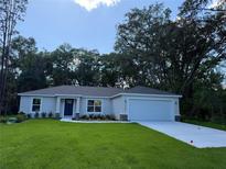 Charming single-story home featuring a well-manicured lawn and an attached two-car garage at 14268 Se 27Th Ct, Summerfield, FL 34491