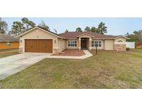 Tan house with brown roof, stone accents, and a wooden garage door at 4933 Sw 109Th Loop, Ocala, FL 34476