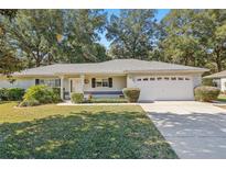 Single-story house with a white garage door and landscaped lawn at 14146 Sw 112Th Cir, Dunnellon, FL 34432