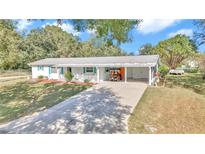 White house with carport, green lawn, and mature trees at 9981 Sw 101St Pl, Ocala, FL 34481