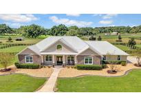 Aerial view of a luxurious ranch-style home with a metal roof, stone accents, and expansive green pastures at 12000 S Highway 475, Ocala, FL 34480