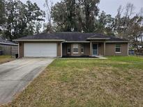 House exterior featuring a garage and well-maintained lawn at 3752 Se 130Th St, Belleview, FL 34420