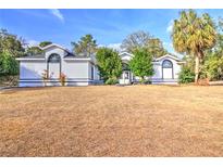 White one-story house with a large yard and mature trees at 10043 Sw 202Nd Cir, Dunnellon, FL 34431