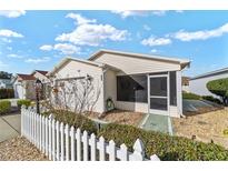 Charming single-story home featuring a white picket fence, screened-in porch, and well-maintained landscaping at 1112 Carvello Dr, The Villages, FL 32162