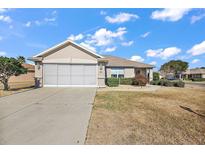 Tan one-story house with screened garage and landscaping at 14315 Se 85Th Ave, Summerfield, FL 34491