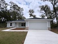 Newly constructed home with gray exterior, attached garage, and landscaping at 17715 Sw 113Th Pl, Dunnellon, FL 34432