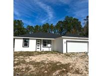 Newly constructed home with a white exterior, black accents, and a two-car garage at 2657 Sw 176Th Loop, Ocala, FL 34473