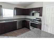 Well-lit kitchen with stainless steel appliances, dark cabinets, and granite countertops at 2792 Sw 161St Loop, Ocala, FL 34473