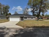 Charming single-story home features a gray exterior, a two-car garage, and a well-maintained front yard at 3957 Se 137Th Ln, Summerfield, FL 34491