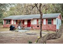 Charming single-story home featuring brick accents, red shutters, and a cozy front porch seating area at 5625 Sw 181St Ct, Dunnellon, FL 34432