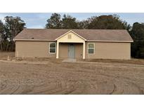 Tan single story house with a light gray front door and covered porch at 5885 Sw 169Th Ct, Ocala, FL 34481