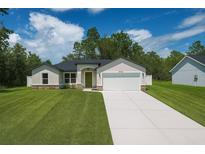 Charming single-story home featuring a well-manicured lawn, attached two-car garage, and welcoming green front door at 7747 Sw 146Th Lane Rd, Ocala, FL 34473