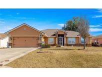 Single-story home with a two-car garage and landscaped lawn at 8217 Sw 61St Ct, Ocala, FL 34476