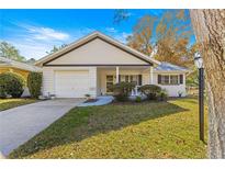 White house with a gray roof, a two-car garage, and a landscaped lawn at 8890 Sw 96Th St # D, Ocala, FL 34481