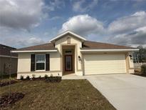 Charming single-story home featuring a two-car garage, landscaped front yard, and a welcoming red front door at 4421 Sw 90Th Pl, Ocala, FL 34476