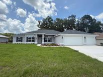 Charming one-story home with a three-car garage, well-manicured lawn, and beautiful landscaping at 13 Nw 45Th Loop, Ocala, FL 34475