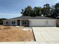 New home with a wide driveway leading to a two-car garage and a lawn ready for landscaping at 13 Nw 45Th Loop, Ocala, FL 34475