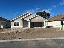 New construction home with a light beige exterior, two-car garage, and landscaping at 4429 Sw 90Th Pl, Ocala, FL 34476