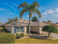 Single-story home with beige exterior, blue shutters, and palm trees at 13579 Se 89Th Terrace Rd, Summerfield, FL 34491