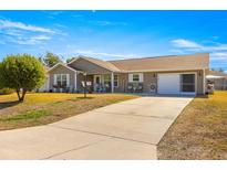 Single-story home with a long driveway, attached garage, and rocking chairs on the porch at 6490 Sw 84Th St, Ocala, FL 34476