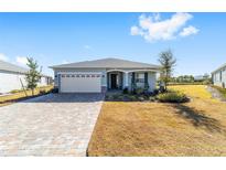 One-story home with light gray siding, paver driveway, and landscaped yard at 7865 Sw 89Th Cir, Ocala, FL 34481