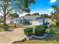 Single-story home with attached garage, landscaping, and a long driveway at 8594 Sw 61St Ct, Ocala, FL 34476