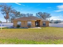 One-story home with tan exterior, landscaped lawn, and white fence at 15391 Se 90Th Ct, Summerfield, FL 34491