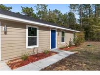 Charming single-story home showcasing a blue front door and neatly landscaped front yard at 15982 Sw 30 Ln, Ocala, FL 34481