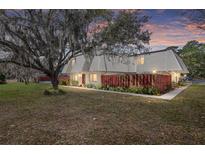 Charming townhouse with a well-maintained lawn, mature tree, and a red privacy fence at sunset at 2145 Ne 45Th Ave # 2145, Ocala, FL 34470