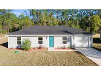 Newly constructed home with gray siding, teal door, and attached garage at 24025 Nw Foxglove Lane, Dunnellon, FL 34431