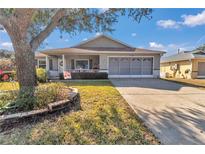 Charming home featuring a large tree, well-maintained lawn, covered porch, and an attached garage at 9708 Sw 97Th St, Ocala, FL 34481