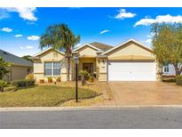 Charming one-story home with a well-manicured lawn, a palm tree and a two-car garage at 12595 Se 97Th Terrace Rd, Summerfield, FL 34491