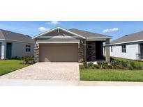 Beautiful single-story home featuring a two-car garage, paver driveway, stone accents, and well-maintained landscaping at 4056 Nw 44Th Cir, Ocala, FL 34482