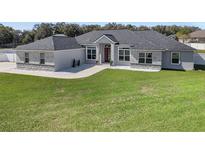 Stunning single-story home featuring a manicured lawn, gray roof, and a beautiful red front door at 6215 Se 13Th St, Ocala, FL 34472