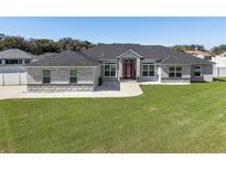 Beautiful single-story home featuring a well-manicured lawn and a striking brick and gray color scheme at 6215 Se 13Th St, Ocala, FL 34472