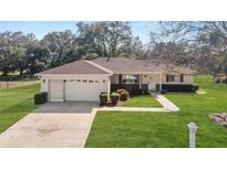 Charming single-story home with a well-manicured front lawn, concrete driveway and an attached garage at 13779 Sw 115Th Cir, Dunnellon, FL 34432