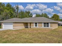 Charming ranch-style home featuring a two-car garage and a well-maintained lawn at 38 Juniper Loop Way, Ocala, FL 34472