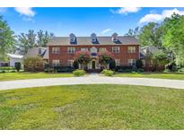 Stately two-story brick home featuring a circular driveway, manicured lawn and mature trees, creating an inviting curb appeal at 4940 E Fort King St, Ocala, FL 34470