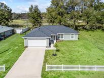 Charming single-story home featuring a well-manicured lawn, white picket fence, and attached two-car garage at 14605 Sw 20Th Pl, Ocala, FL 34481