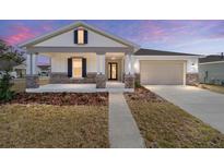 Charming single-story home featuring a covered porch with stone accents and a two-car garage at 5589 Sw 78Th Ave Rd, Ocala, FL 34474