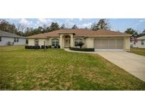 Charming home boasts a spacious front yard, beautiful landscaping, and an inviting entryway with an arched portico at 10884 Sw 53Rd Cir, Ocala, FL 34476