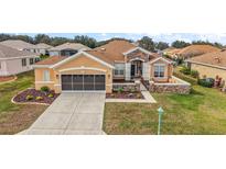 Charming exterior with a brown roof, stucco walls, landscaping, and a two-car garage at 13096 Se 93Rd Terrace Road, Summerfield, FL 34491