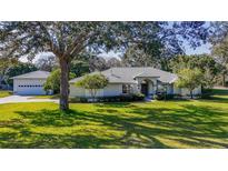 Inviting single-story home with a well-manicured lawn and mature trees providing ample shade at 1712 Ne 40Th Ave, Ocala, FL 34470