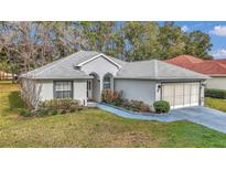 Charming single-story home featuring a well-manicured lawn, complemented by a driveway and an attached two-car garage at 6793 Sw 111Th Loop, Ocala, FL 34476