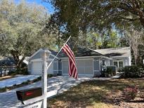 Charming single story home with tidy landscaping, an American flag and a brick driveway at 8045 Sw 115Th Loop, Ocala, FL 34481