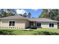 Charming single-story home with a well-manicured lawn, neutral color, and large windows at 8498 Sw 129Th Terrace Rd, Dunnellon, FL 34431